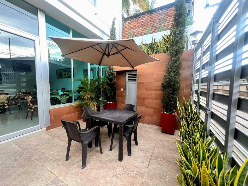 Terraza con mesas y parasol junto a jardín vertical